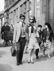 6th April 1962: French actors Sami Frey and Brigitte Bardot are followed by fans as they walk on Boulevard Richard-Lenoir, Paris, France. Both wear dark sunglasses; Bardot wears a kerchief with a tweed skirt suit. (Photo by Agence France Presse/Agence France Presse/Getty Images)